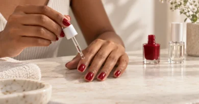 Mãos com unhas vermelhas recebendo gotas secantes para acelerar a secagem do esmalte