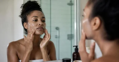 Mulher negra realizando esfoliação facial com produto suave para cuidados com a pele.