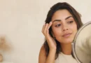 Mulher observando sobrancelhas recém-aplicadas em um espelho com expressão de dúvida