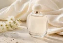 frasco de perfume elegante sobre tecido claro com flores brancas e luz suave