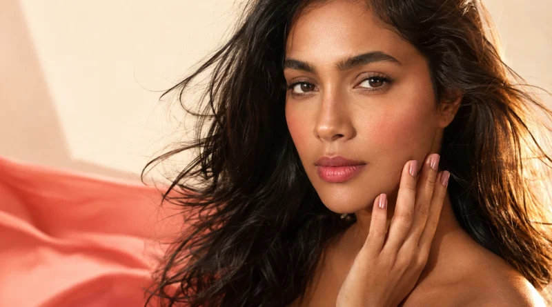 mulher com maquiagem leve de primavera, blush coral, unhas rosadas e cabelo com movimento