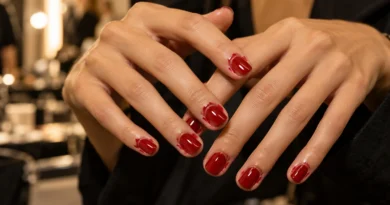 Boyfriend nails com esmalte vermelho borrado de propósito ao redor das unhas.