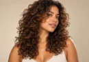 Mulher com corte butterfly cacheado, camadas ao redor do rosto e volume natural.