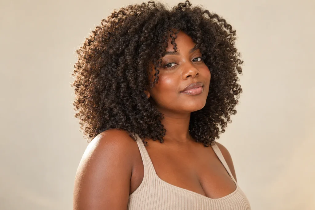 Mulher com cachos 3C e corte butterfly adaptado ao volume e ao encolhimento natural.