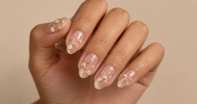 Unhas encapsuladas delicadas com pequenas flores brancas em base nude rosada.