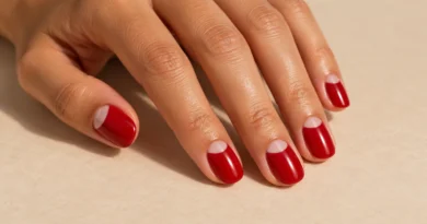Esmaltação meia-lua: como fazer a nail art clássica com um toque moderno Unhas meia-lua com esmalte vermelho e semicírculo transparente próximo às cutículas.